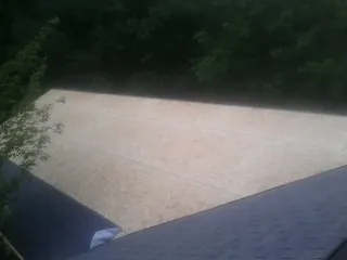 New OSB roof sheathing installed beside an existing shingle roof in Cameron